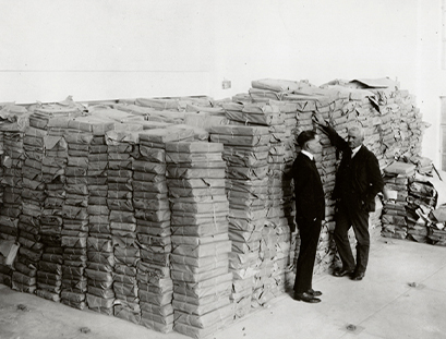 Ralph Lutz and colleague stand next to a huge stack of collections material circa 1920