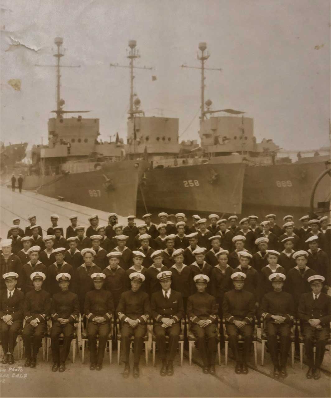 Sepia colored photo of Commander Kao Tsu (fifth from the left) and the entire crew in front of the warships that China took over from the US Navy under lend-lease arrangements, ca. December 1945.