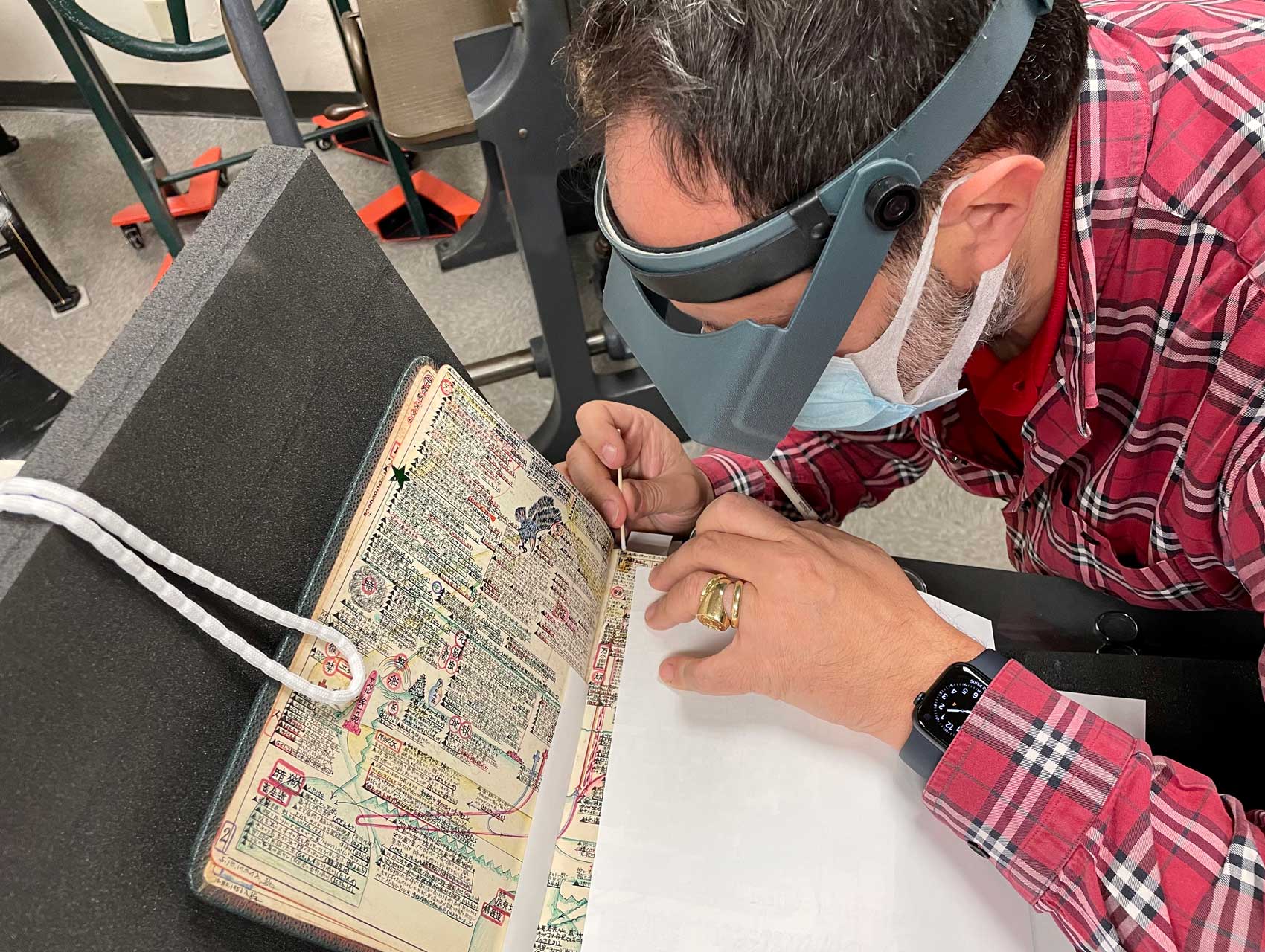 Laurent Cruveillier wearing magnifying goggle during conservation treatment of the Kitaji Bibles