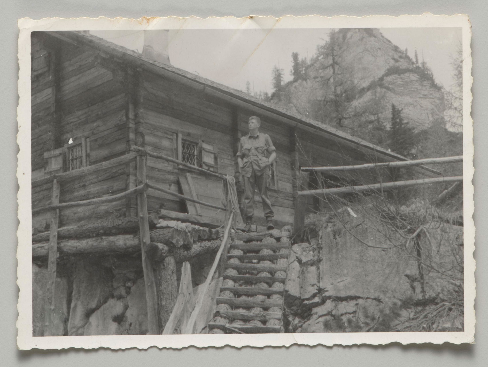 US soldier Donald Wayne Richardson standing in front of a log cabin.