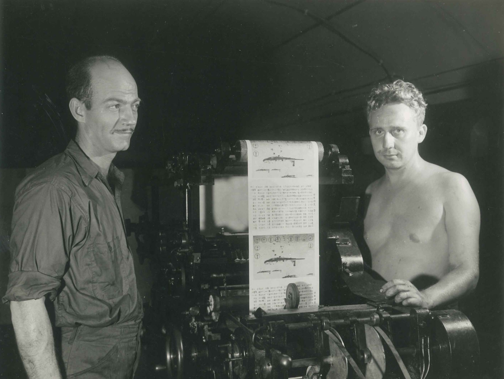 Two men operating a print press at the Office of War Information