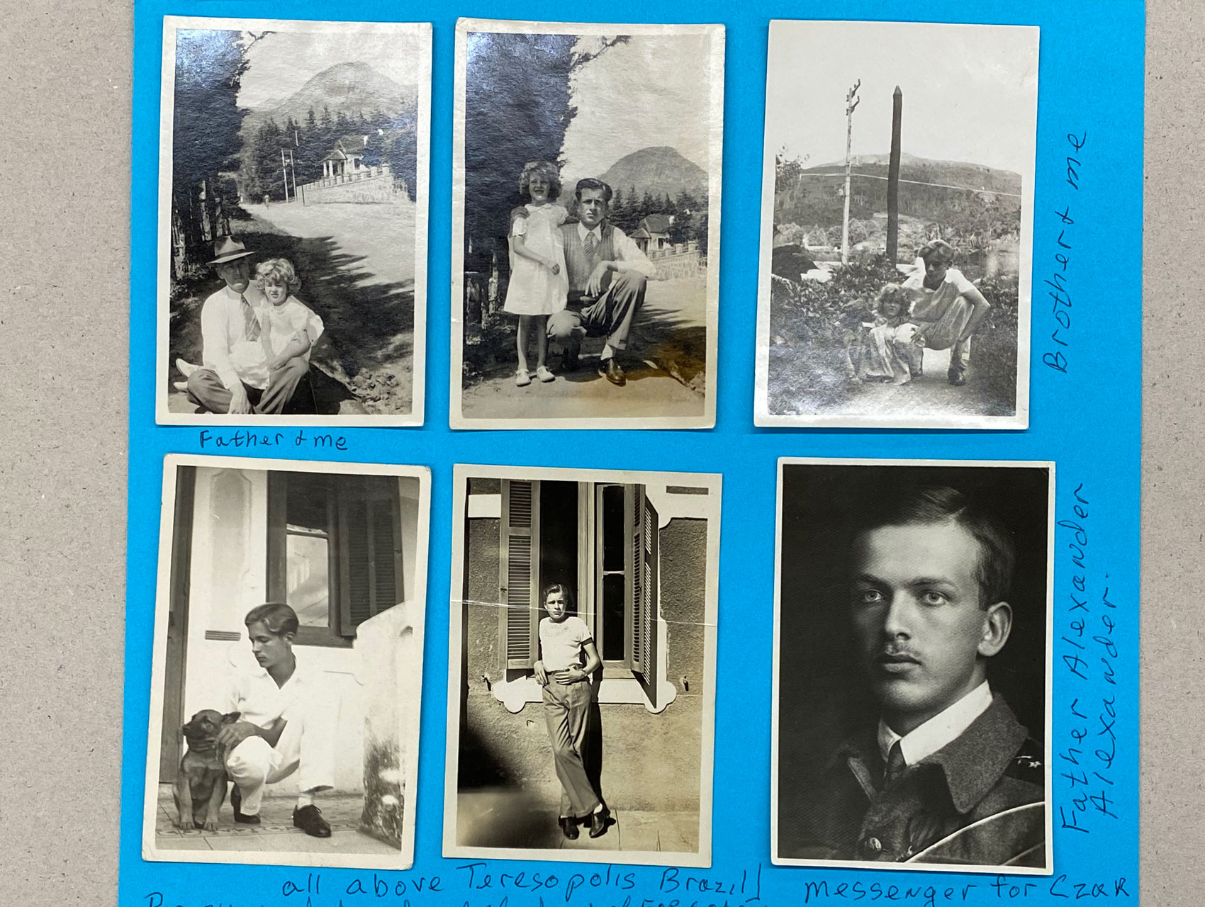 Six black and white photographs adhered to blue paper.
