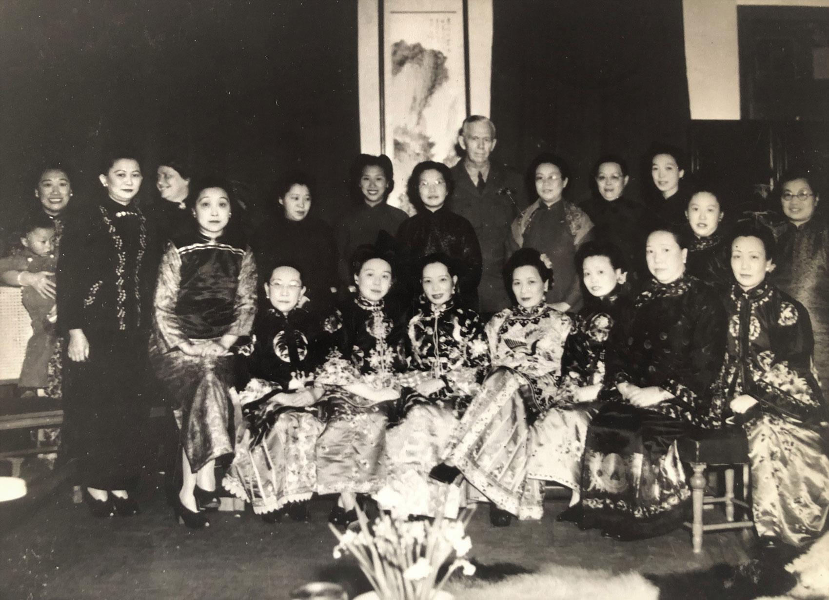 Black and white photo of a group of women and one made dressed for a Christmas holiday group photo