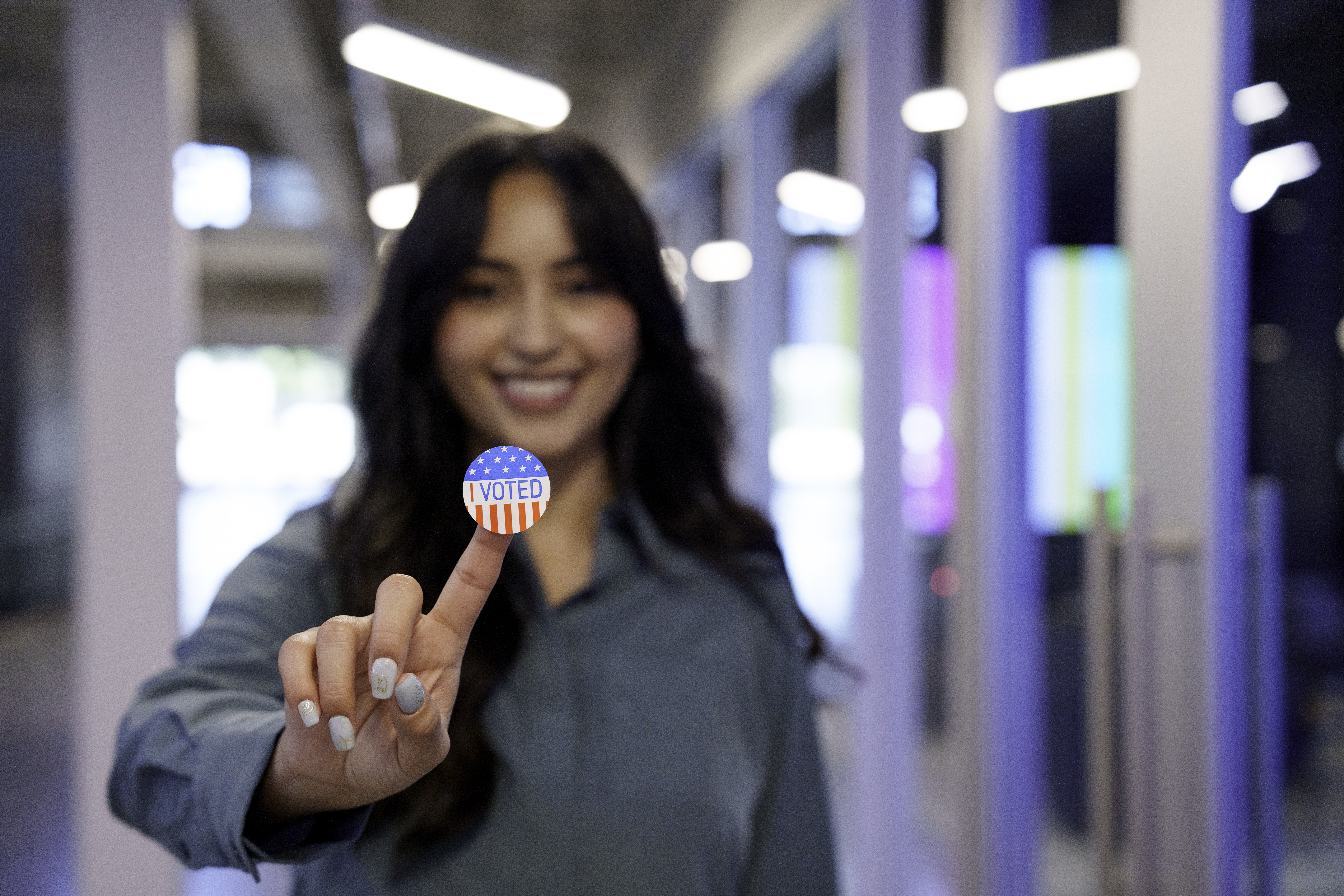 Young Hispanic Woman in Her Twenties Proudly Displaying Her I Voted Sticker in a Co-Working Space stock photo