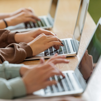 Teenage girls using typing on laptops stock photo