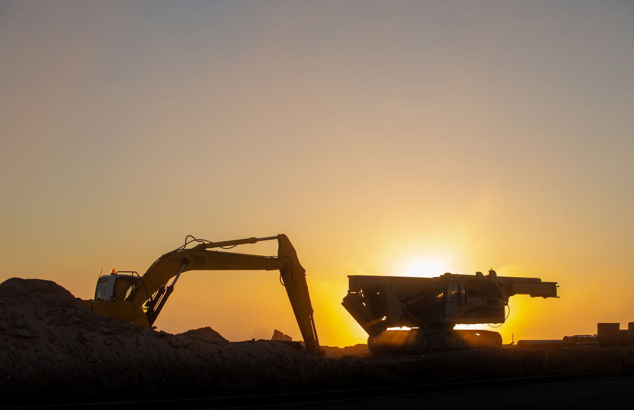 Construction machinery in the rays of the rising sun, early morning at the construction site stock photo