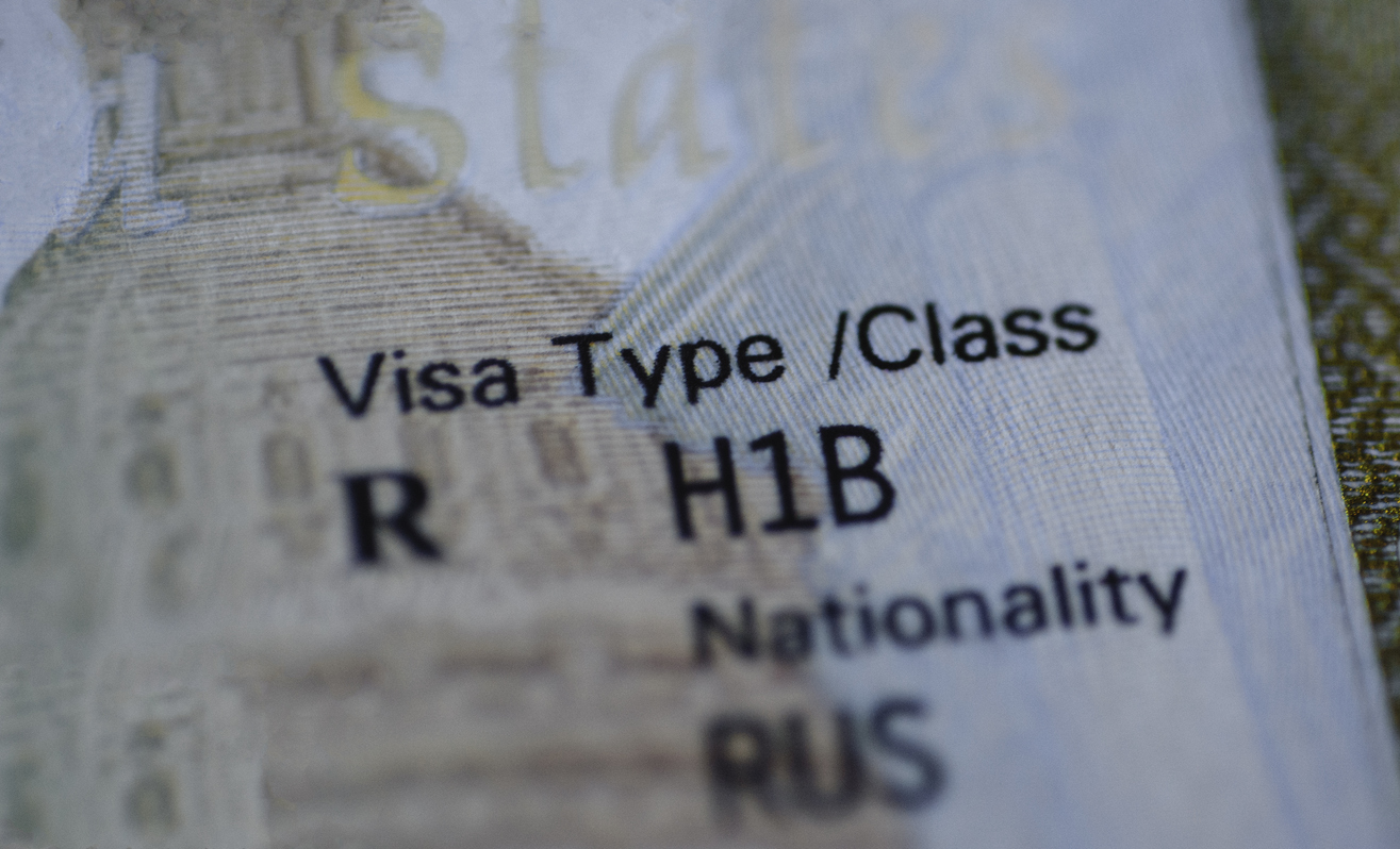 Fragment of H1B visa (for specialty workers) stamp in passport, blurred april calendar on background. H1B visa program deadline concept. Close up view. stock photo