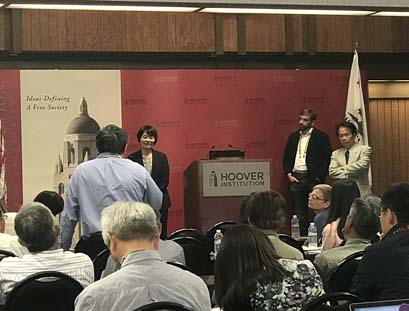 people standing by a podium in front of a group of people at a workshop