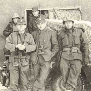7 military men standing in front of a jeep