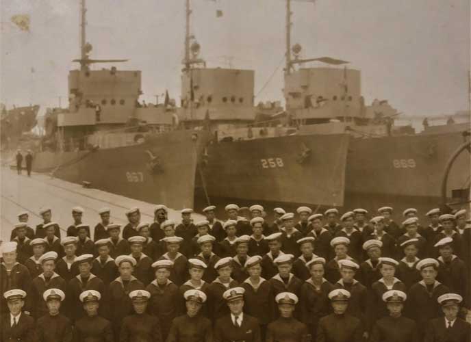 Sepia colored photo of Commander Kao Tsu (fifth from the left) and the entire crew in front of the warships that China took over from the US Navy under lend-lease arrangements, ca. December 1945.