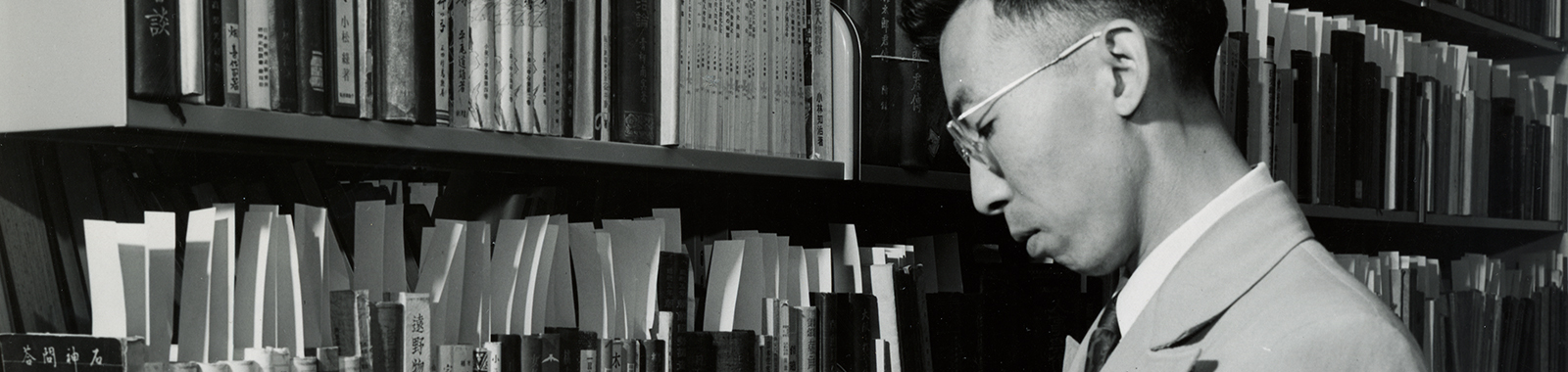 Black and white photo of a researcher looking at Hoover's Asian library stacks