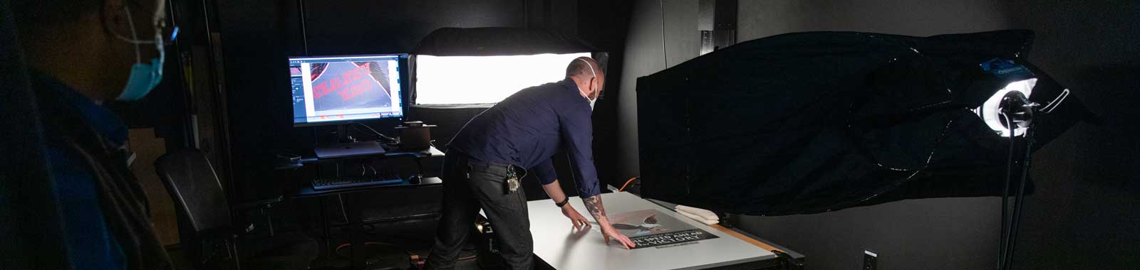 Man in digitization lab imaging a poster on a table