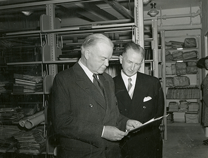 Photo of Herbert Hoover and Ralph Lutz looking at material in Hoover Tower stacks
