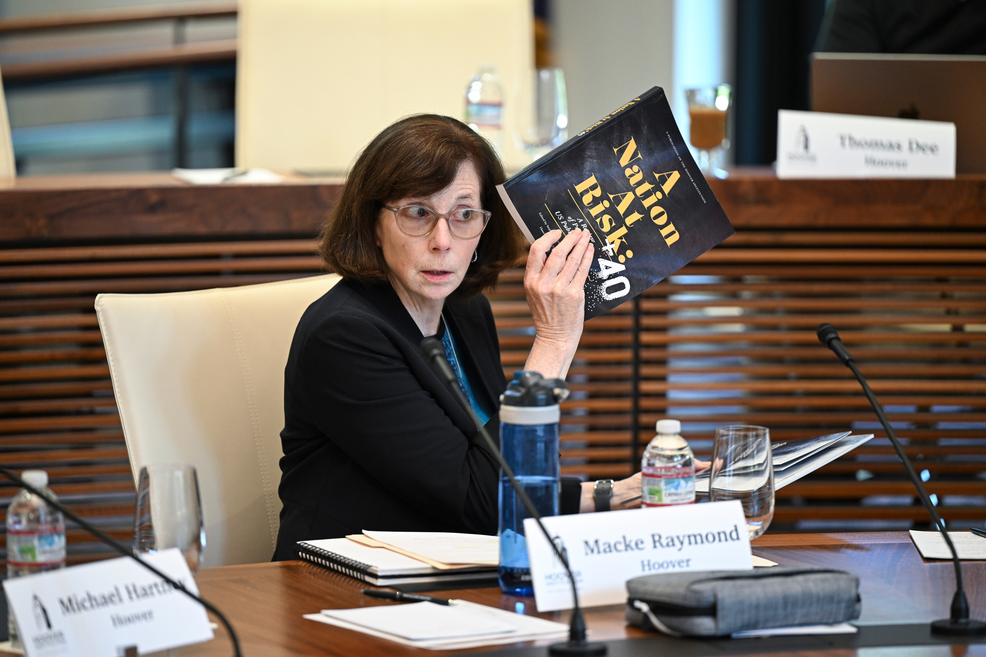 Distinguished Research Fellow Margaret (Macke) Raymond holds a copy of Hoover’s A Nation At Risk +40 report while speaking with state education system leaders on May 15, 2025. (Rod Searcey)