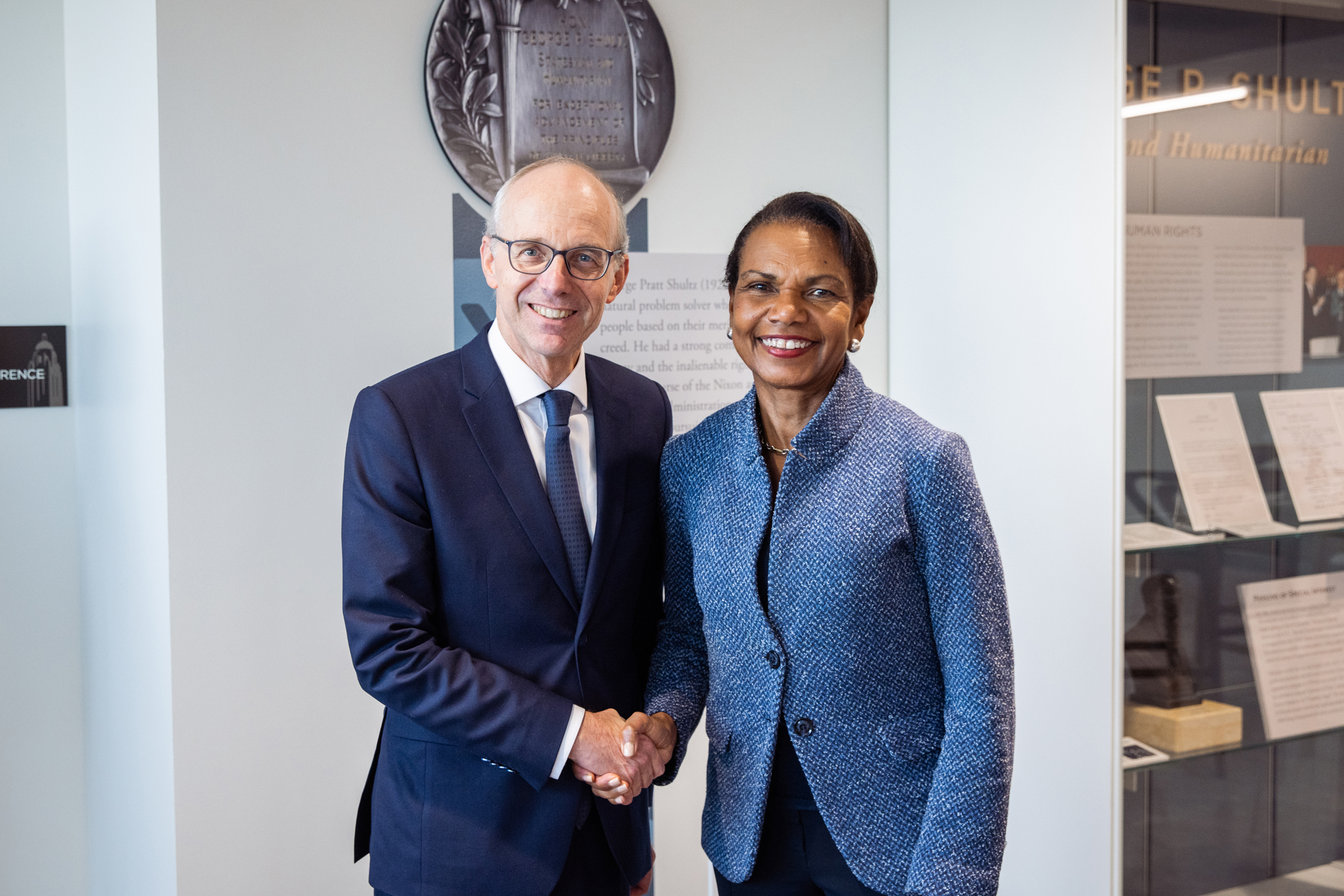 Luxembourg Prime Minister Luc Frieden and Hoover Institution Director Condoleezza Rice shake hands in Hoover’s George P. Shultz Building on November 11, 2025. (Patrick Beaudouin) 