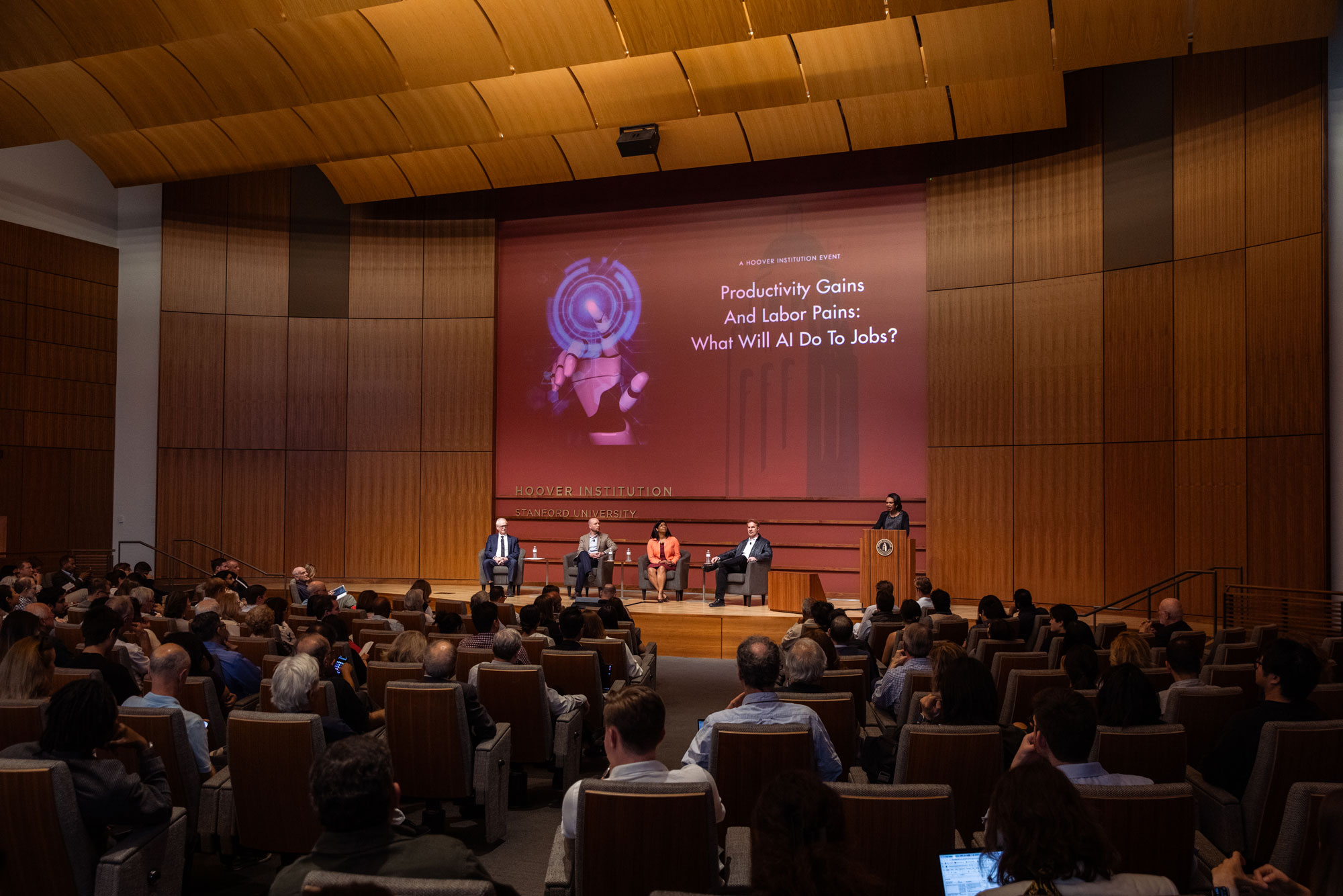 Hoover Research Director Steven J. Davis (left), Anthropic Head of Economics Peter McCrory, LinkedIn Chief Economist Karin Kimbrough and Erik Brynjolfsson of the Stanford Digital Economy Lab are seen in Hauck Auditorium alongside Hoover Institution Director Condoleezza Rice on March 17, 2026. (Patrick Beaudouin)