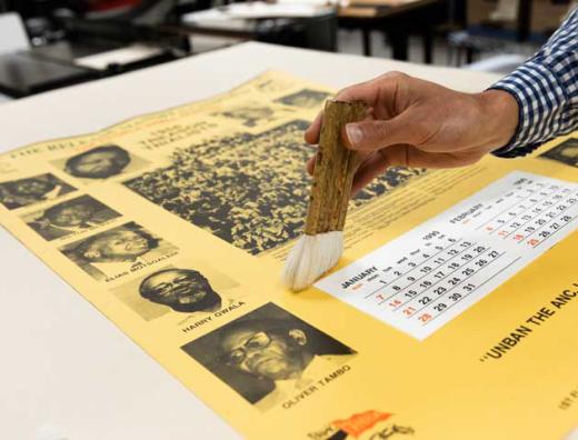 hand holding a brush over yellow colored poster