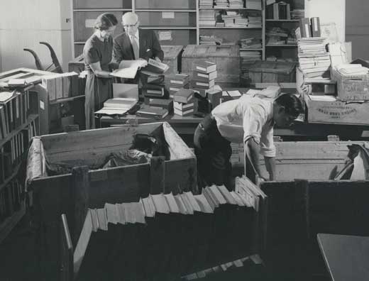 two people standing and one person bending to open crates