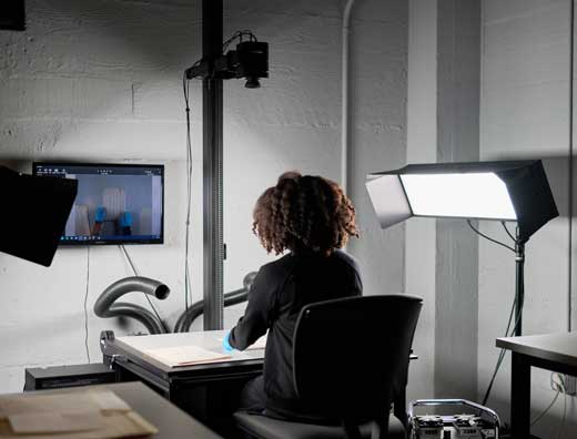 Photographer sitting in a chair in the digitization lab imaging archival material