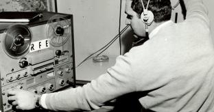 RFE/RL black and white photo of man wearing headphones sitting in front of a radio console