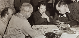 Black and white photo detail showing American and Japanese officials deliberating at the end of World War II