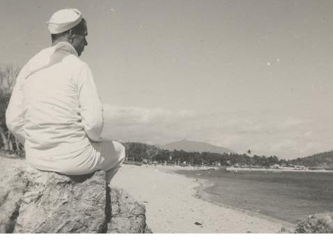 US Navy Seabee sits on a rock at a beach in the Pacific theater of World War II