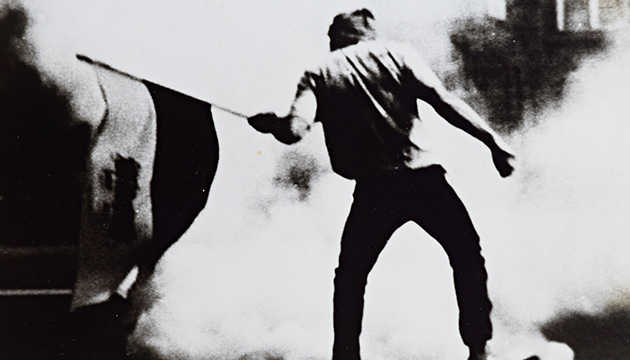 Black and white photograph of a Polish protester waving Solidarity flag, circa 1981–1983