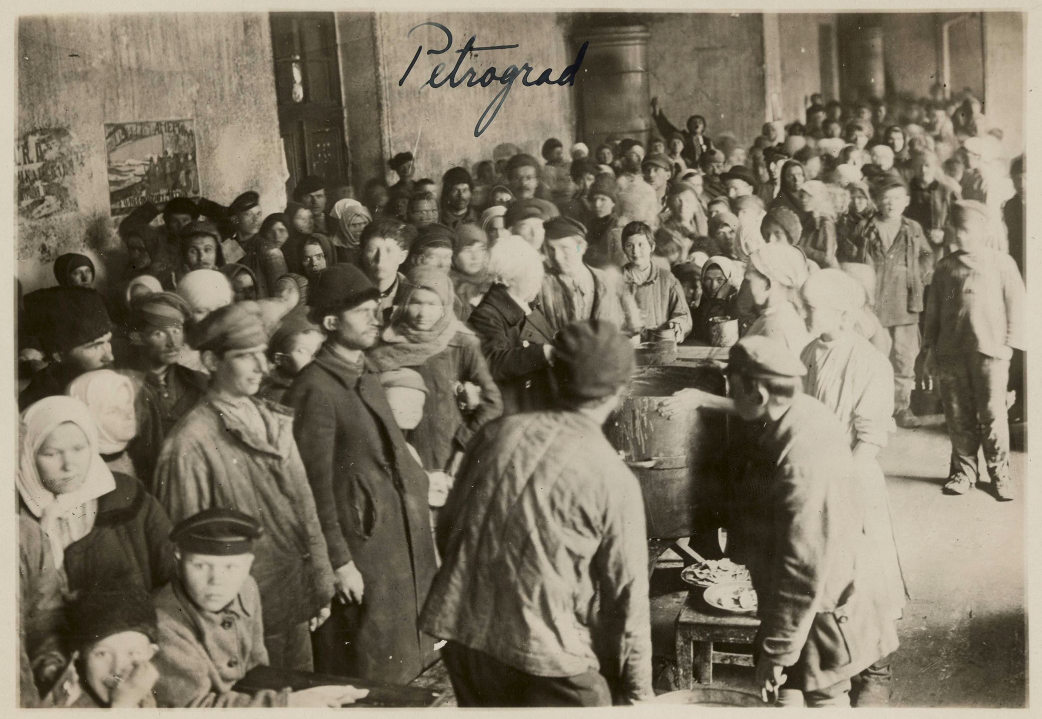 Black and white photograph showing a large crowd of mostly adults waiting to receive food rations.