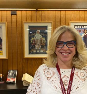 Roxanne Peck standing in front of a wall of posters and books on a table