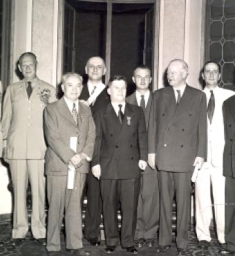 Group of men standing for a photo. Nicholas Feodoroff (front row center) with Herbert Hoover (front row right).
