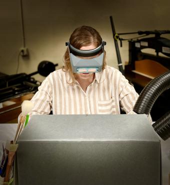 Photograph of person doing conservation work partially hidden by an archival box