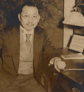 Sepia tone photograph of H. H. Kung seated at desk, 1930s