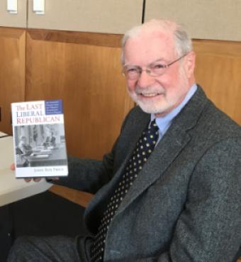 John Roy Price holding a copy of his book on President Nixon