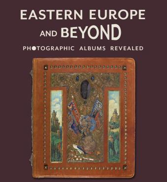 Purple background with title in cream above a leather bound photo album covered in paintings, metalwork, and jewels. Gajda Album