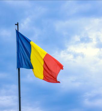 Romanian national flag against romantic sky in Bucharest, Romania - stock photo