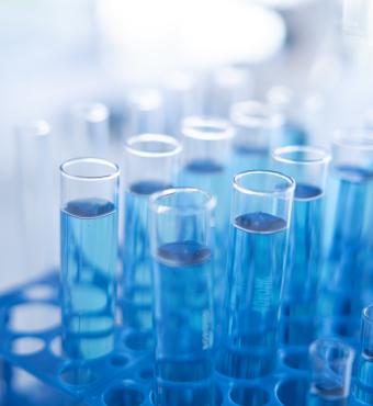 Science laboratory test tubes row with light blue liquid close-up - stock photo