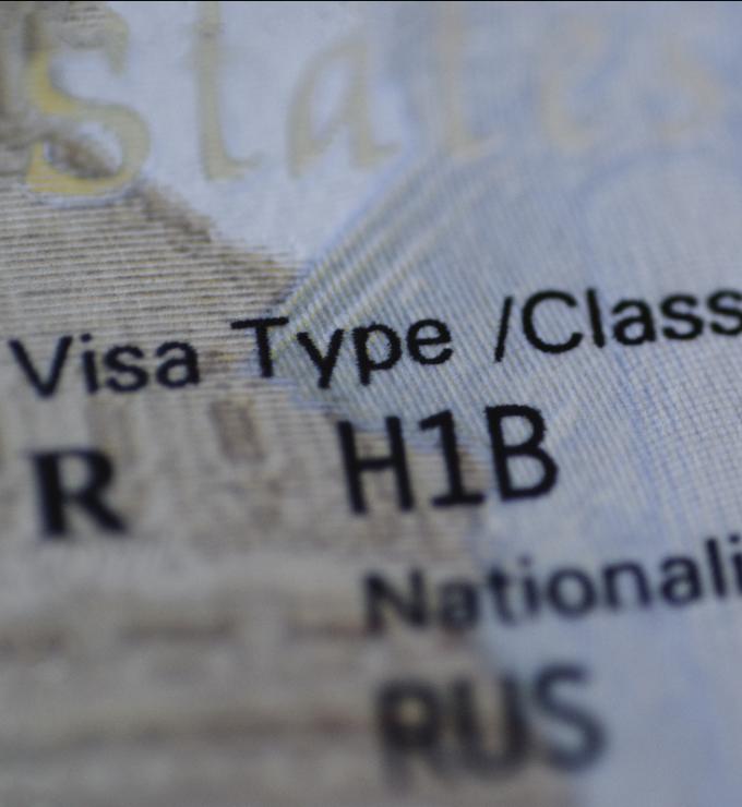 Fragment of H1B visa (for specialty workers) stamp in passport, blurred april calendar on background. H1B visa program deadline concept. Close up view. stock photo