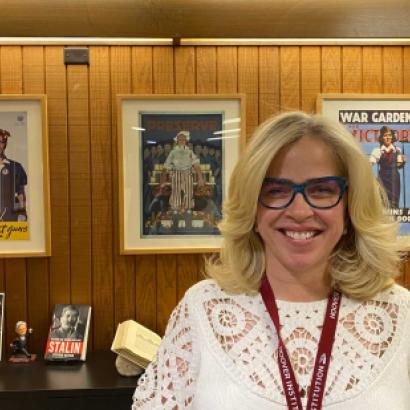 Roxanne Peck standing in front of a wall of posters and books on a table