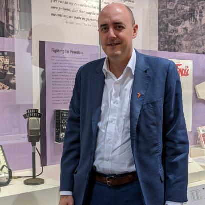 Jamie Fly, president of Radio Free Europe/Radio Liberty visiting Hoover Tower gallery stands next to RFE/FL microphone