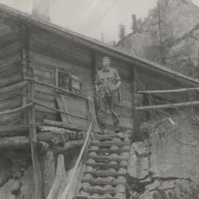 US soldier Donald Wayne Richardson standing in front of a log cabin.