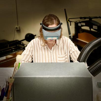 Photograph of person doing conservation work partially hidden by an archival box