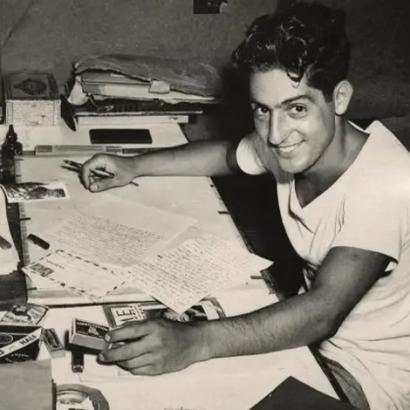 Nat Bellantoni writting a letter at his desk in a tent during World War II