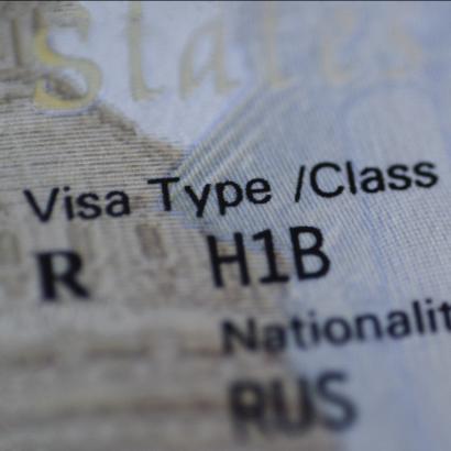 Fragment of H1B visa (for specialty workers) stamp in passport, blurred april calendar on background. H1B visa program deadline concept. Close up view. stock photo