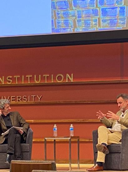 Alex de Waal and Niall Ferguson sitting on the stage of Hauck Auditorium