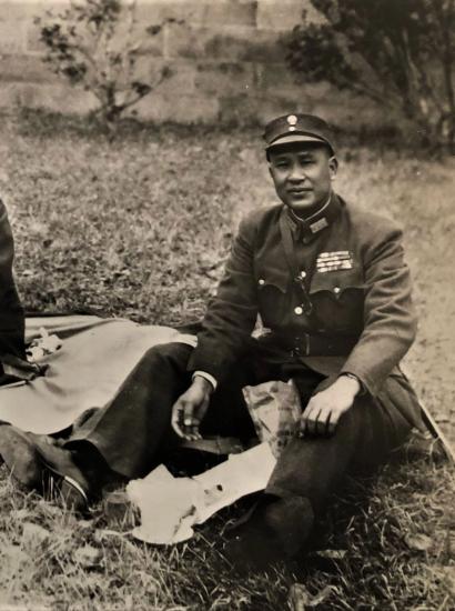 Black and white photo of 3 men dressed in military uniforms sitting on the ground having a picnic.