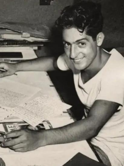 Nat Bellantoni writting a letter at his desk in a tent during World War II
