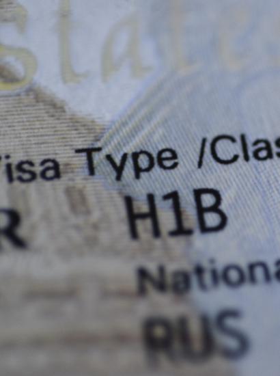 Fragment of H1B visa (for specialty workers) stamp in passport, blurred april calendar on background. H1B visa program deadline concept. Close up view. stock photo