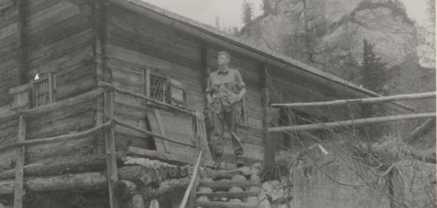 US soldier Donald Wayne Richardson standing in front of a log cabin.