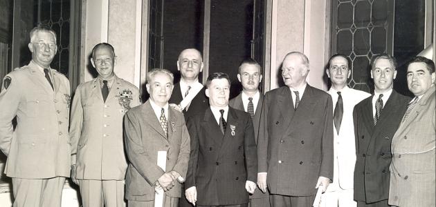 Group of men standing for a photo. Nicholas Feodoroff (front row center) with Herbert Hoover (front row right).