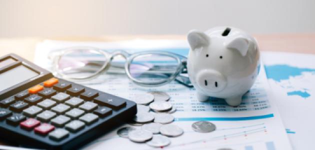 Piggy bank, coins, glasses, and calculator on top of paper